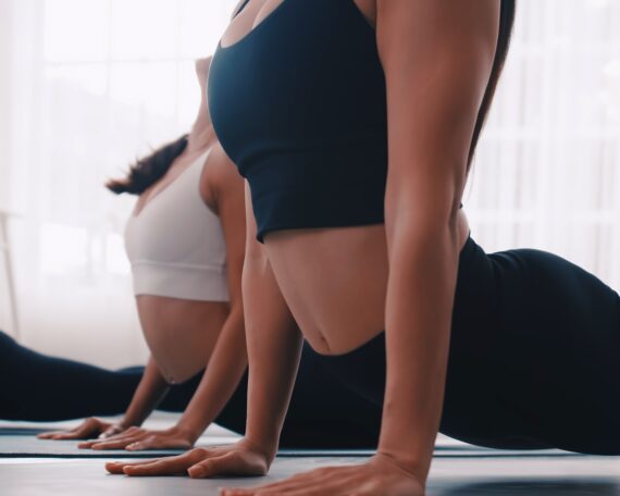 Group of Asian women stretching in yoga class. Group of girls doing Pilates exercises at the gym.
